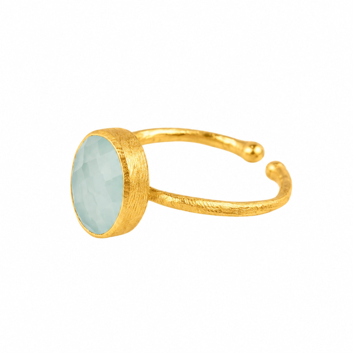 Faceted aqua chalcedony oval in a brushed gold collet on a hammered open gold band on a white background