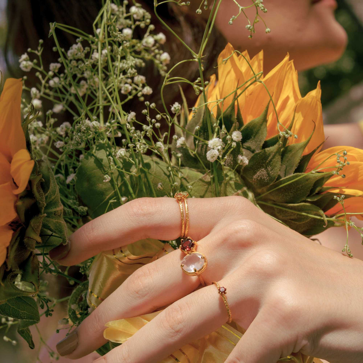 Delicate Vintage Aqua Chalcedony Dotted Band Ring Gold — Hand wearing a gold ring with an aqua chalcedony gemstone, holding yellow flowers. By Protsaah Zurich.