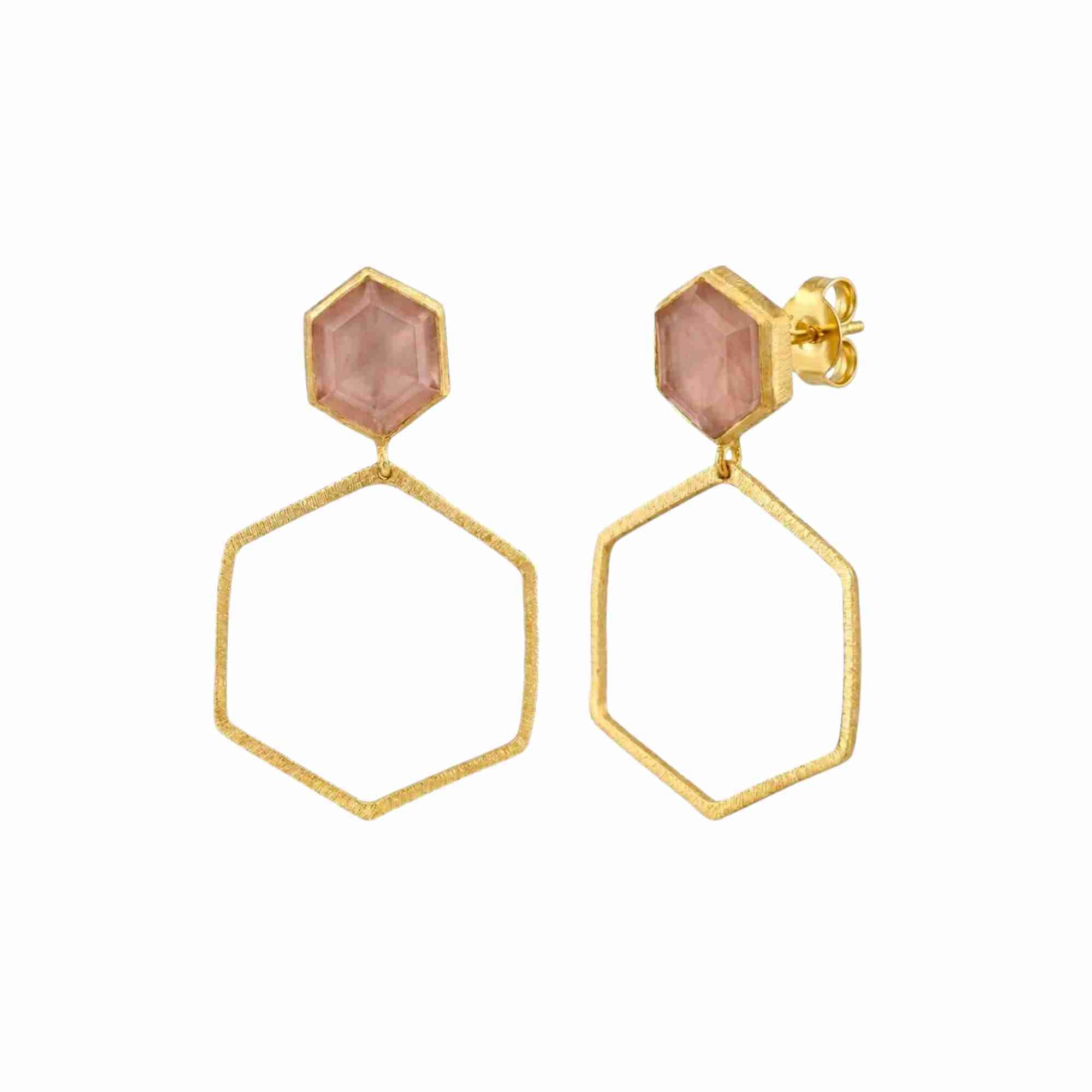 Product photography of Geo Glam Hexagonal Rose Quartz Statement Earrings Gold, highlighting the faceted soft pink gemstone suspended inside a large, open hexagonal drop frame below a hand-textured matte gold post — Protsaah Zurich.