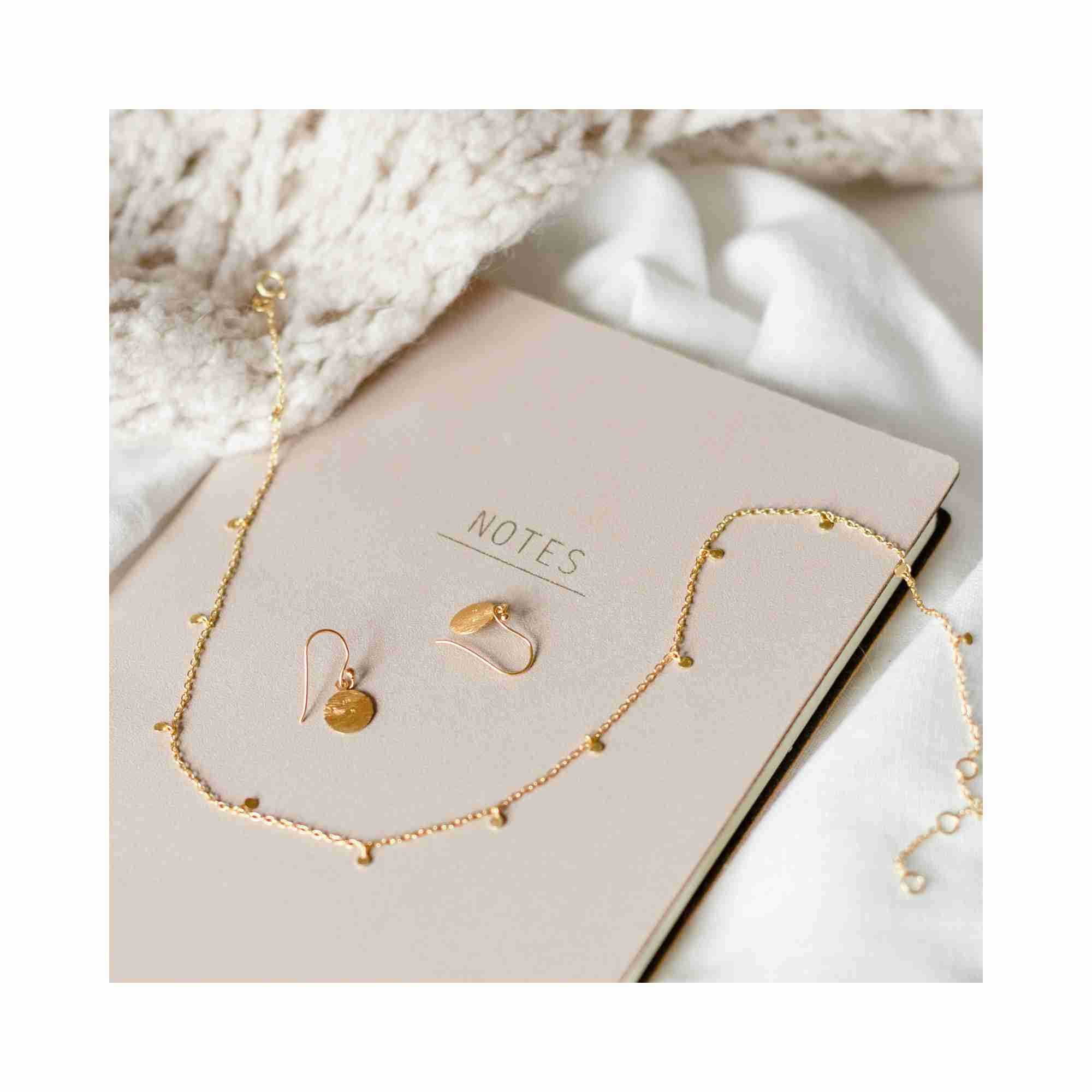 Technical product photoshoot of the Shimmering Disks Constellation gold necklace, highlighting the artisan-crafted hand-applied scratch finish and the intricate circular filigree textures — Protsaah Zurich.