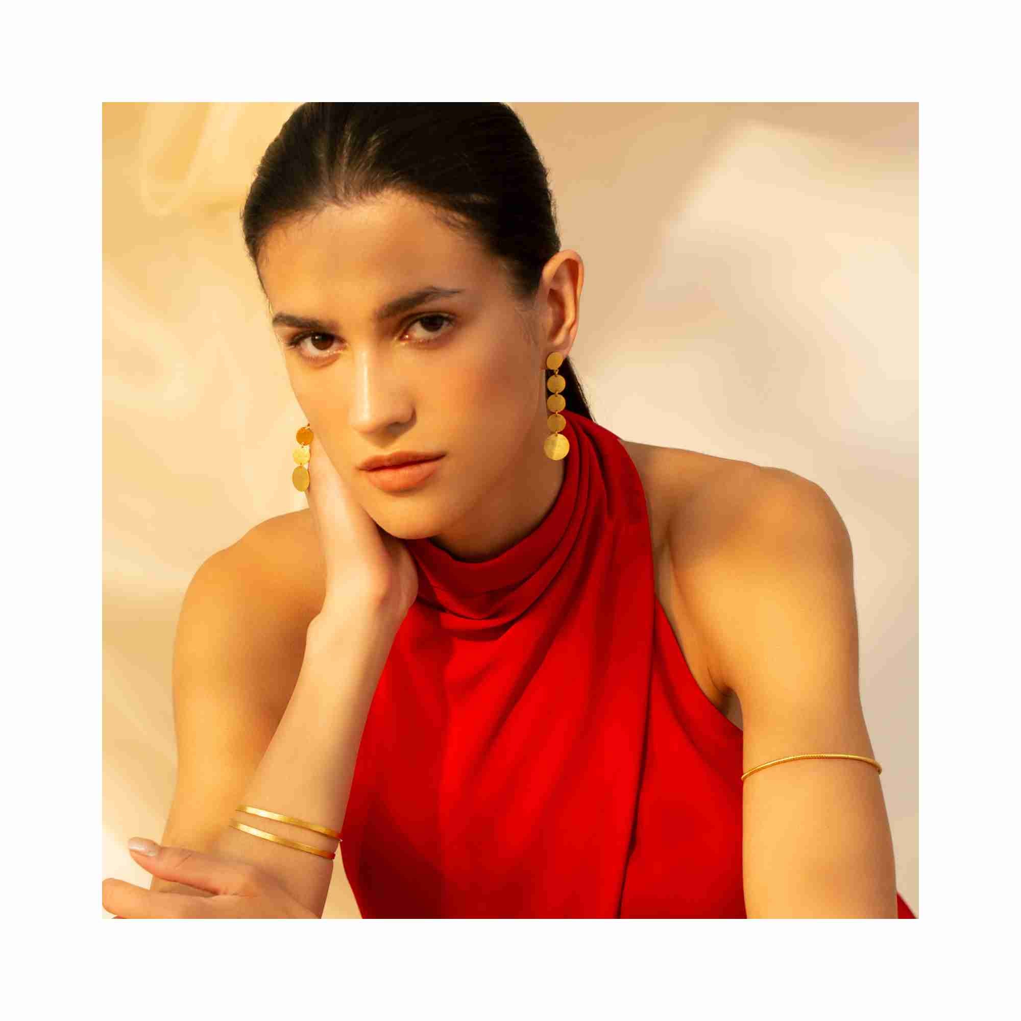 Editorial model photoshoot of Shimmering Disks Graduating Disc Cascade Statement Earrings Gold — featuring a vertical tier of four graduating disks in 22K gold vermeil for a bold, architectural look — Protsaah Zurich.