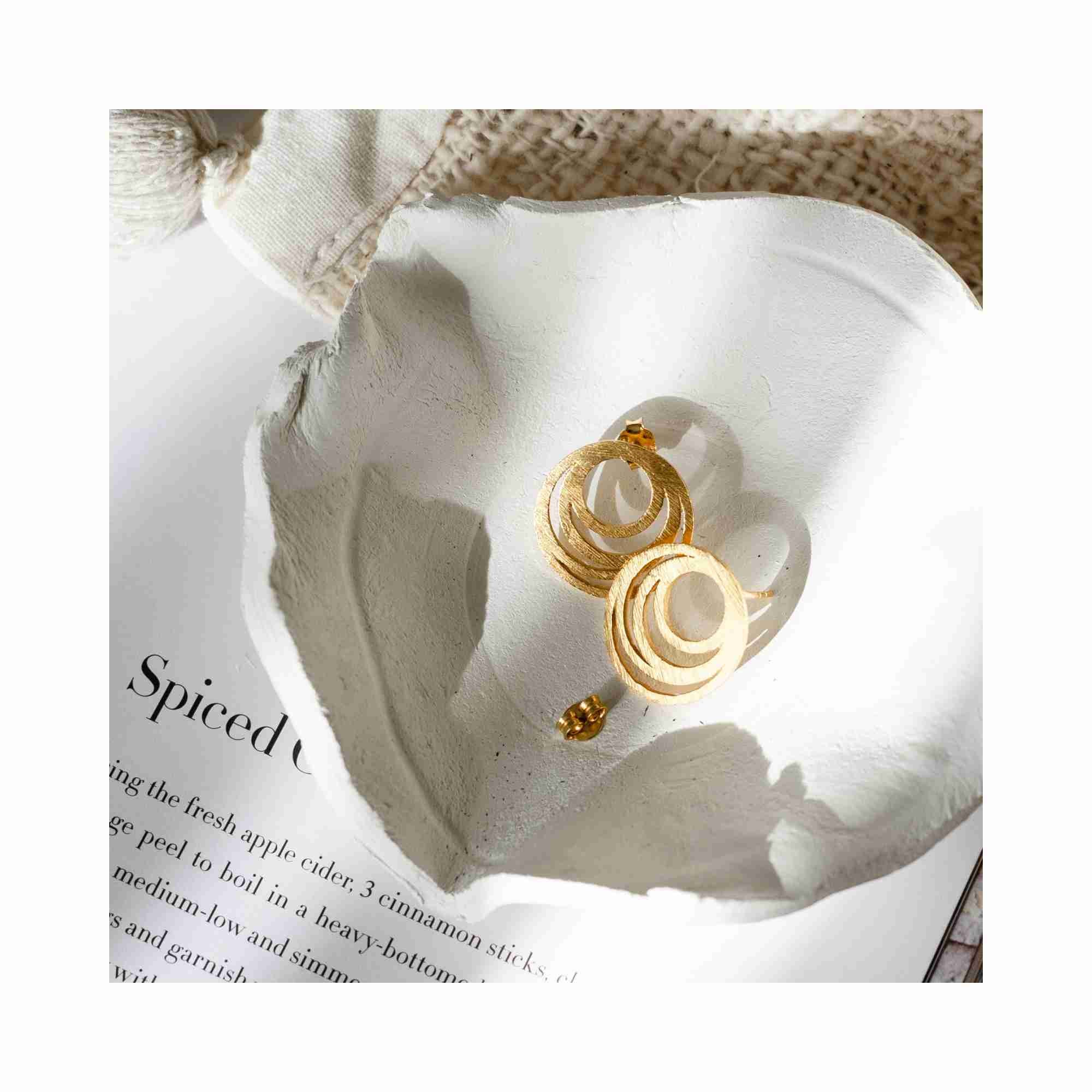 Shimmering Disks Intermingled Circles Stud Earrings Gold — concentric triple ring scratch-finish stud earrings in 22K gold vermeil over 92.5 recycled silver, styled in a white clay bowl with natural linen — Protsaah Zurich