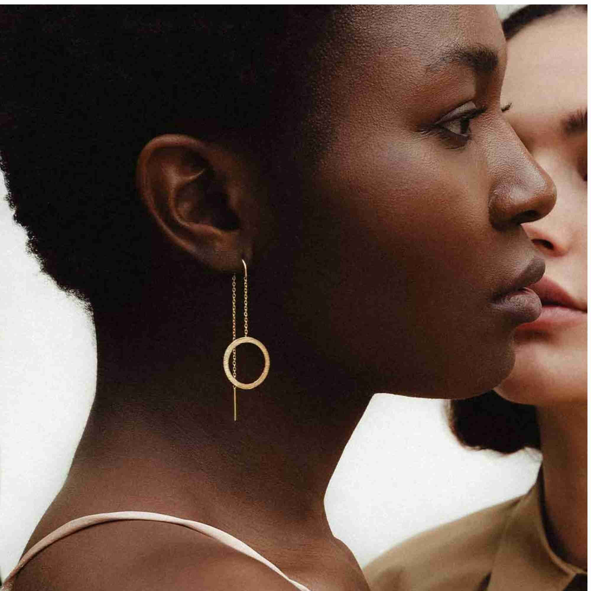 Side profile view of a model wearing the Shimmering Disks Circle Chain Threader Earrings in gold, showing the fine chain threader with a flat circle charm dangling below the earlobe.