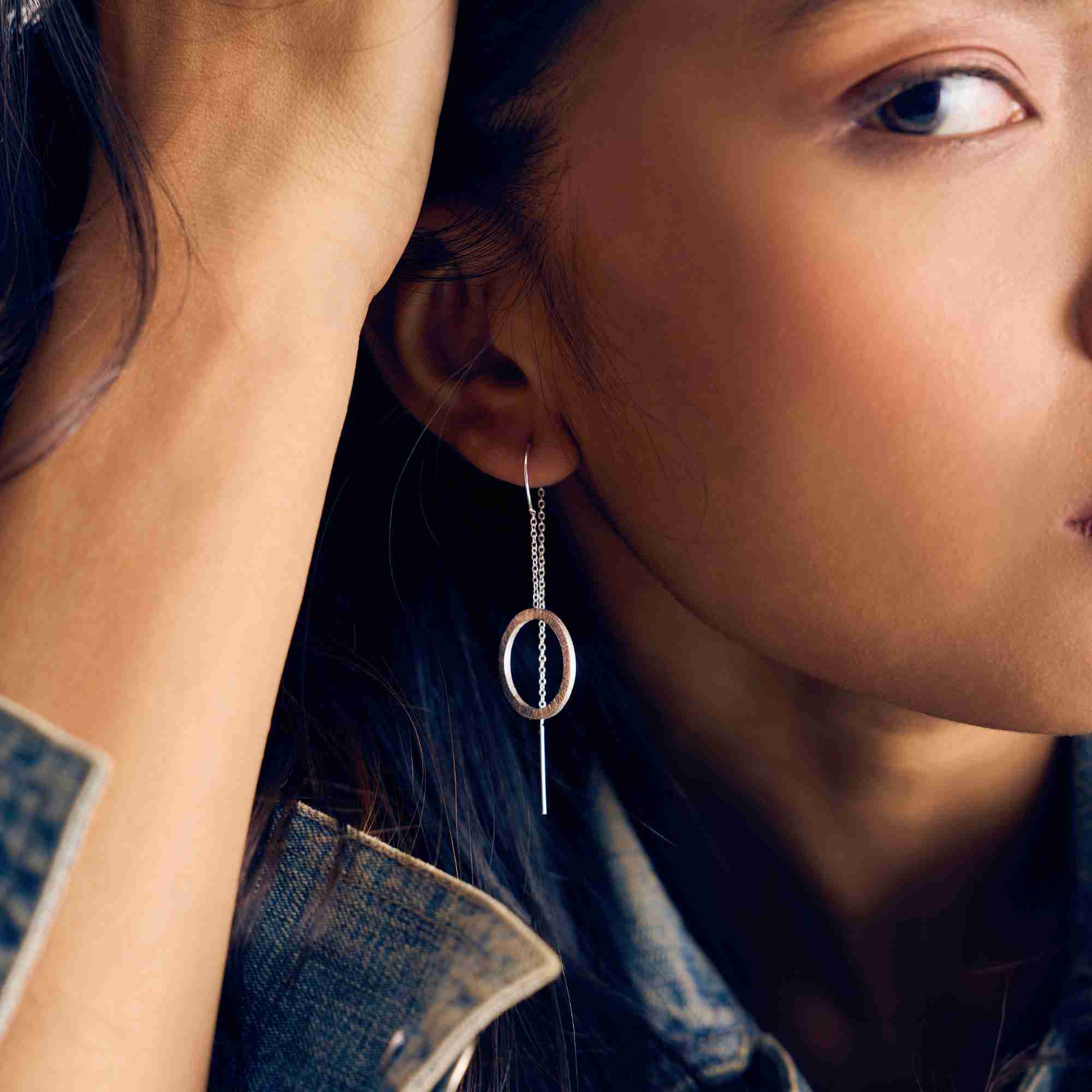 Side profile of a model wearing the silver circle chain threader earring, showing how the open circle hangs from the fine chain.