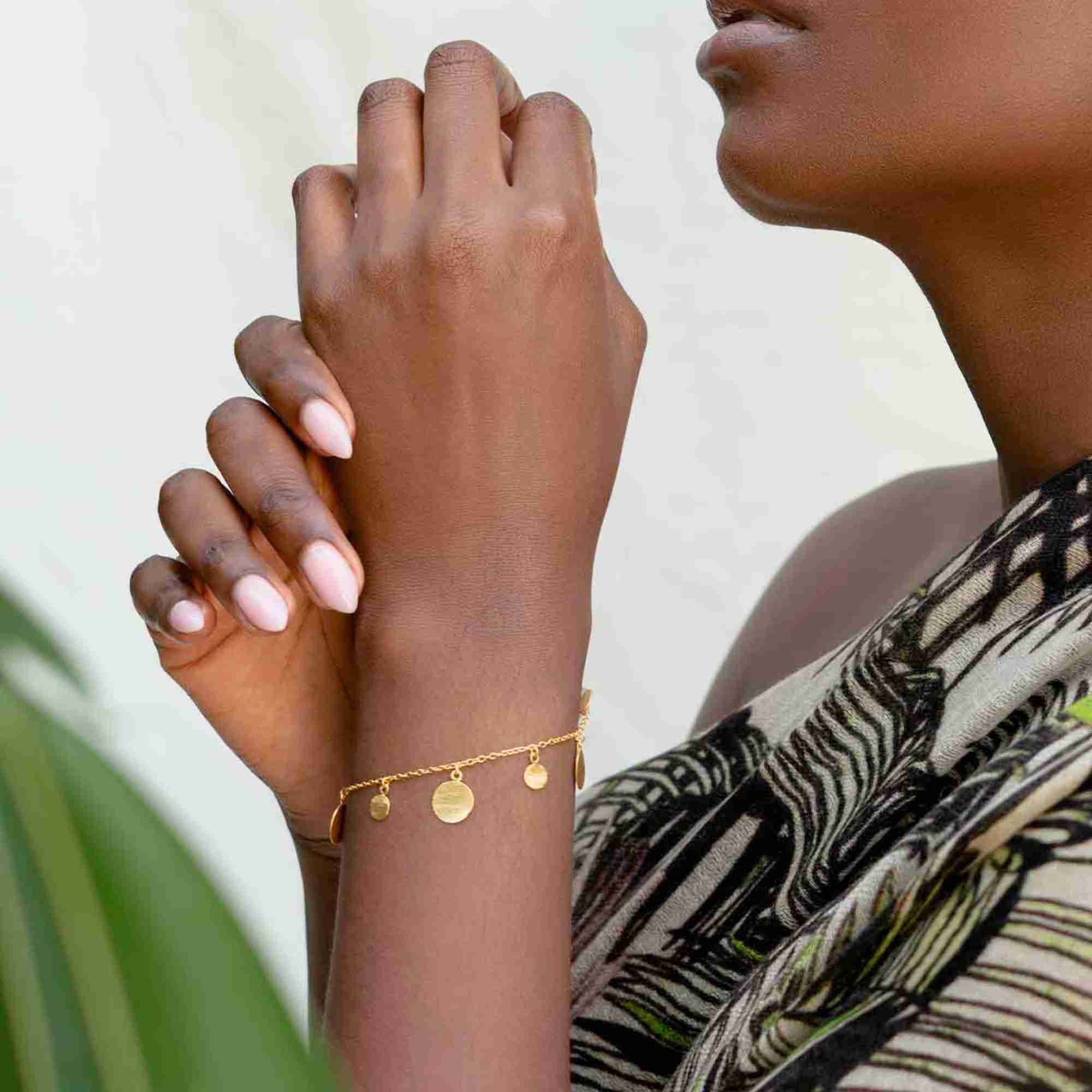Model wearing the Shimmering Disks Delicate Chain Bracelet Gold, showing the minimalist fine trace chain and the central textured gold disc element resting elegantly on the wrist.