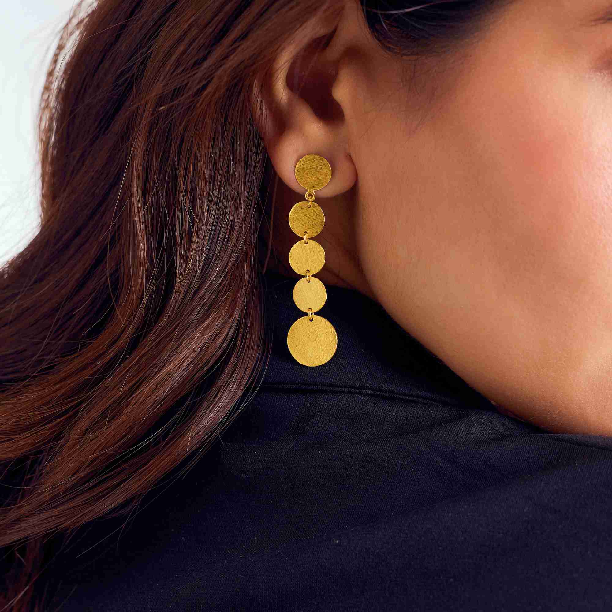 A matching pair of Shimmering Disks Graduating Disc Cascade Statement Earrings Gold arranged neatly on a plain white backdrop, displaying their elegant graduating drop silhouette from small to large.