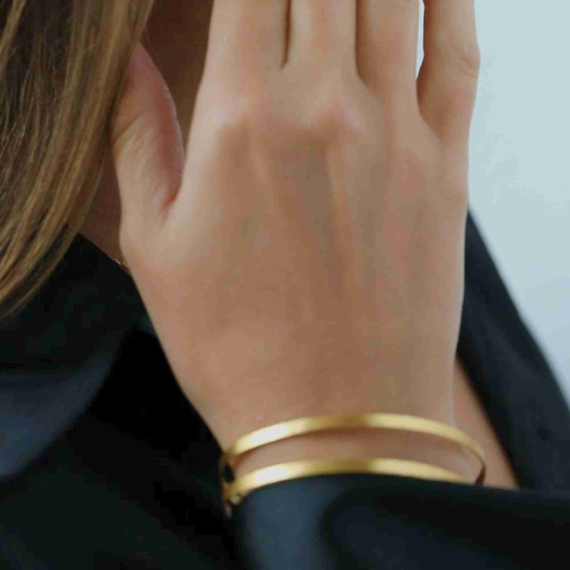Close-up product view of the Shimmering Disks Sculptural Flat-Band Double Cuff Gold centerpiece, showcasing the hand-brushed matte metal finish and clean geometric edges.