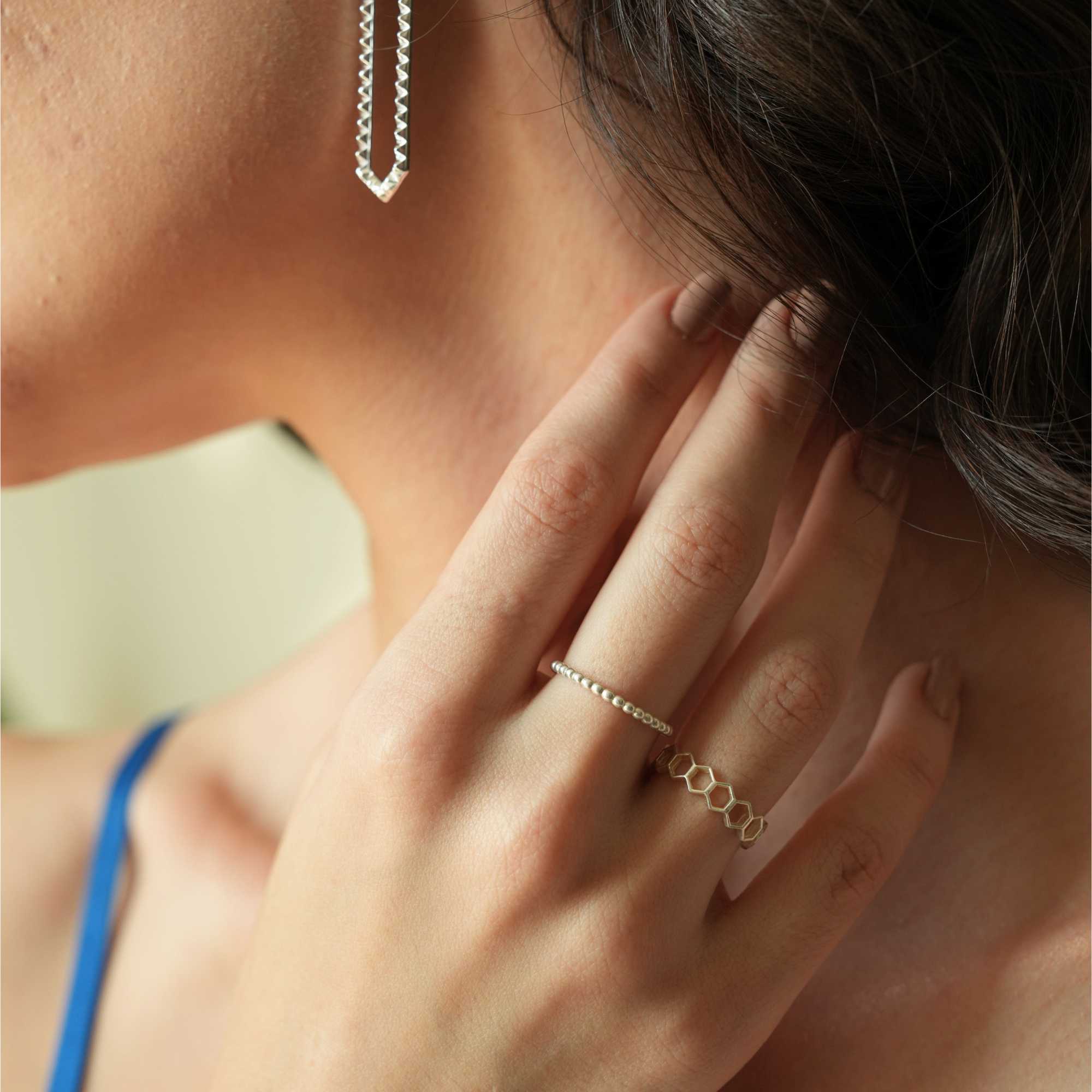 Profile lifestyle image showcasing the Delicate Vintage Beaded Stacking Ring Silver on a model’s index finger as she touches her neck, displaying its fine beaded design alongside a geometric ring, by Protsaah Zurich.