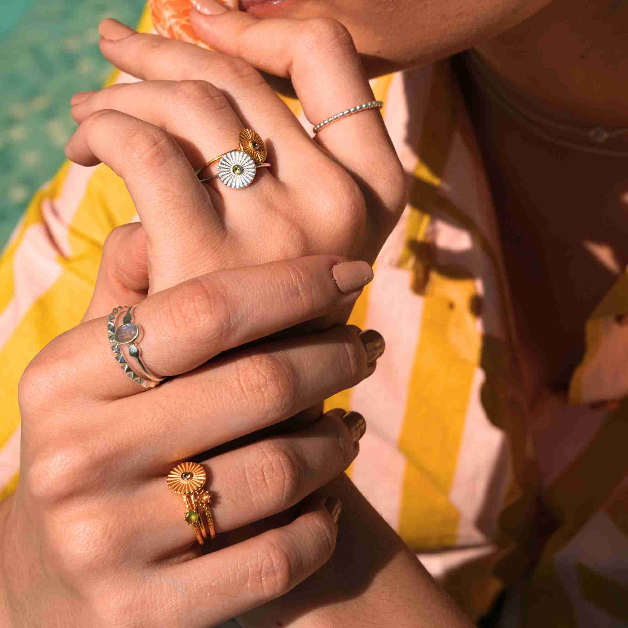 Outdoor lifestyle campaign picture named Delicate Vintage showing a model's hands adorned with mixed-metal jewelry in the sunlight. Worn high on the pinky finger is the minimalist Delicate Vintage Beaded Stacking Ring Silver, crafted from 92.5 recycled sterling silver with a continuous bubble bead texture by Protsaah Zurich.