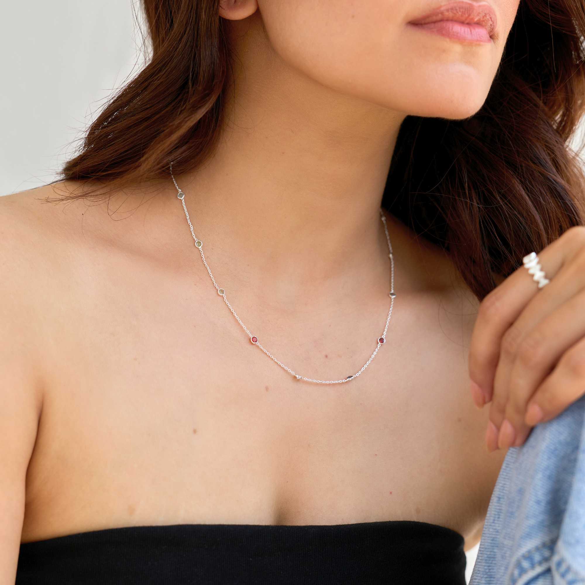 A lifestyle view of the Protsaah Zurich Dew Drops multi-stone silver short necklace styled casually on a model with a black top and denim jacket, highlighting its everyday luxury appeal.