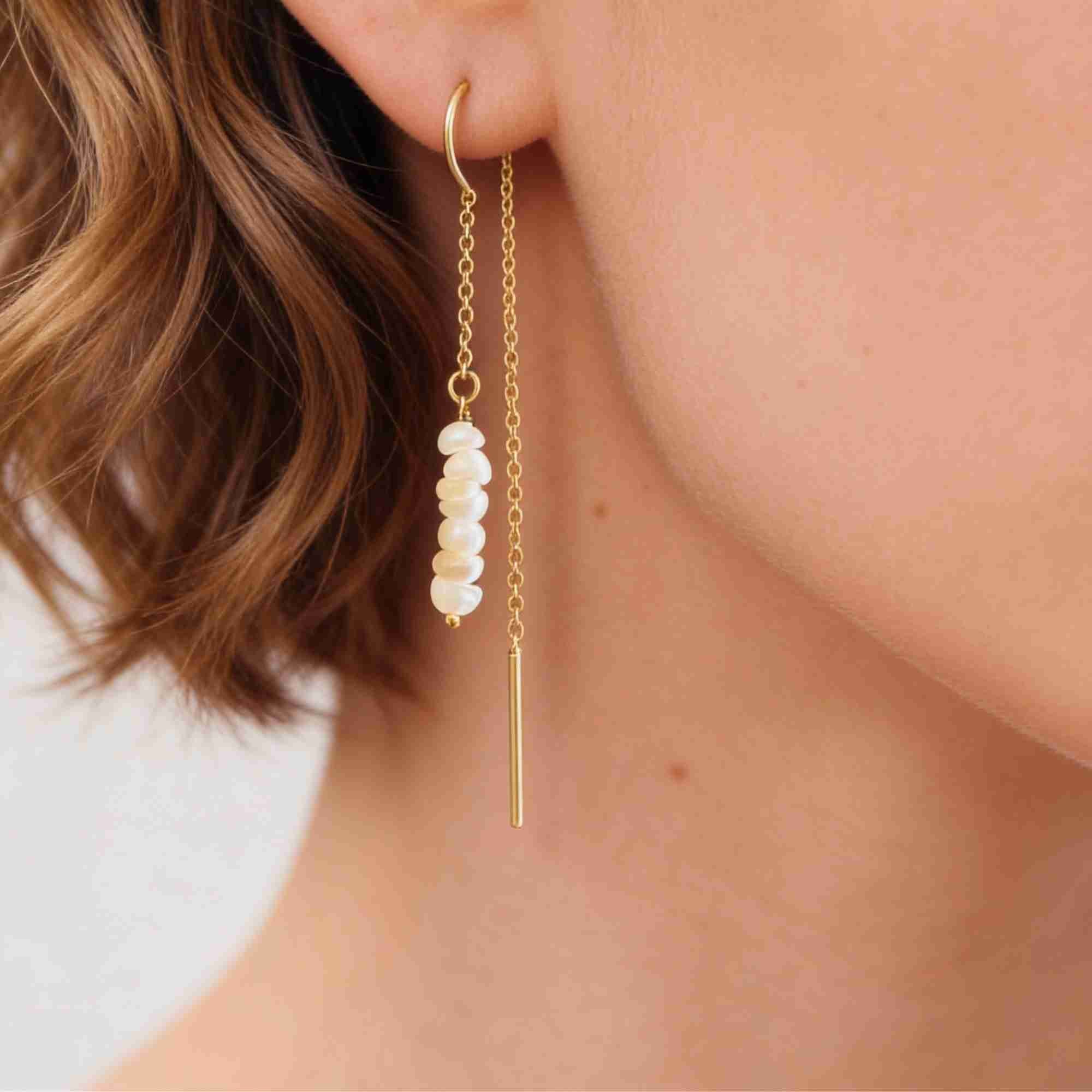 Detailed close-up lifestyle view focusing on the model's ear adorned with the PEARLS GALORE Stacked Seed Pearl Chain Threader Earrings Gold, referencing file name Pearl_Galore_13.jpg. The shot clearly captures the intricate construction of the thin gold chain looping through the ear, with a pin post dangling adjacent to five tightly stacked, round white seed pearls.
