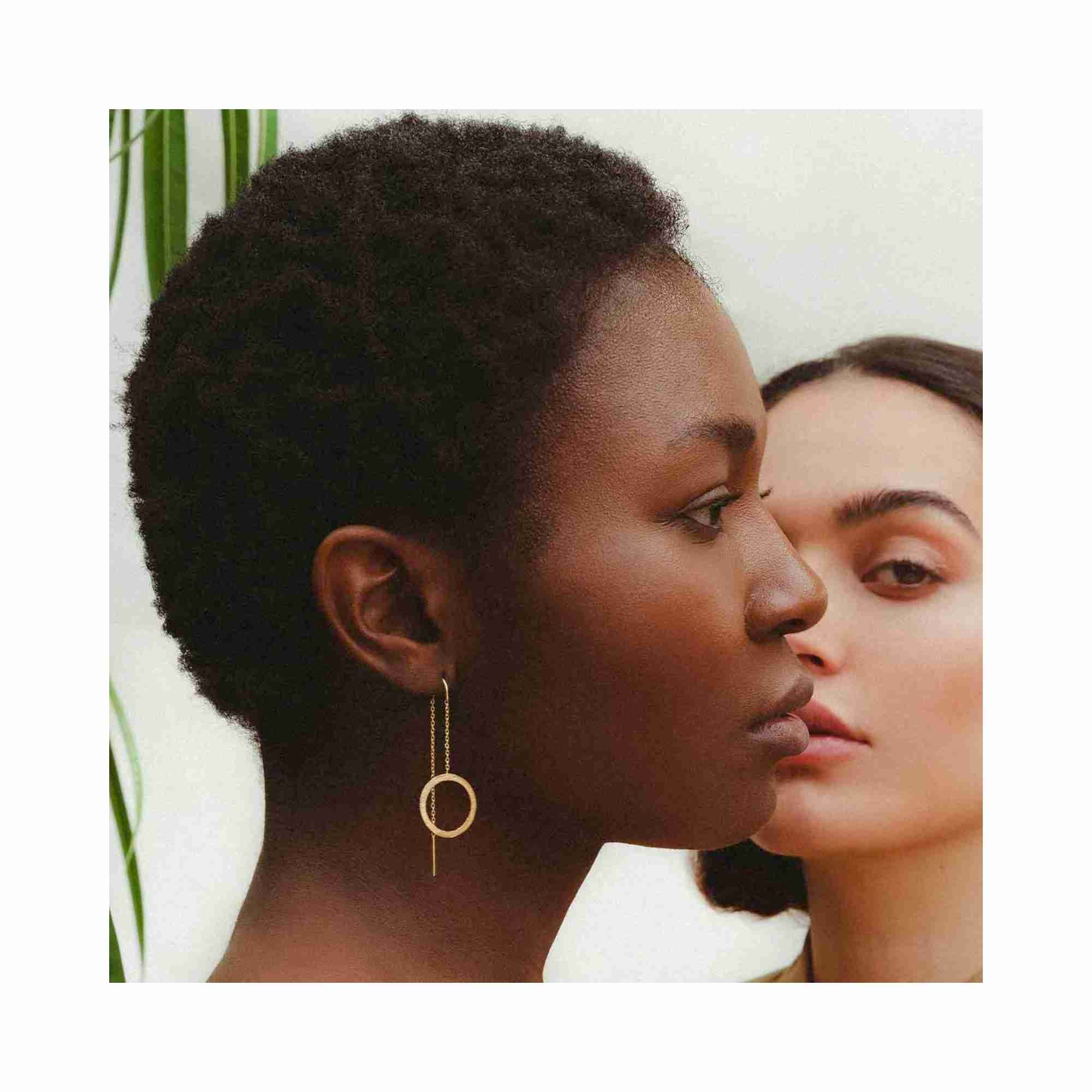 Model wearing the Shimmering Disks gold circle chain threader earrings, showcasing the elegant long drop silhouette and hand-brushed matte gold texture against a clean, minimalist background.