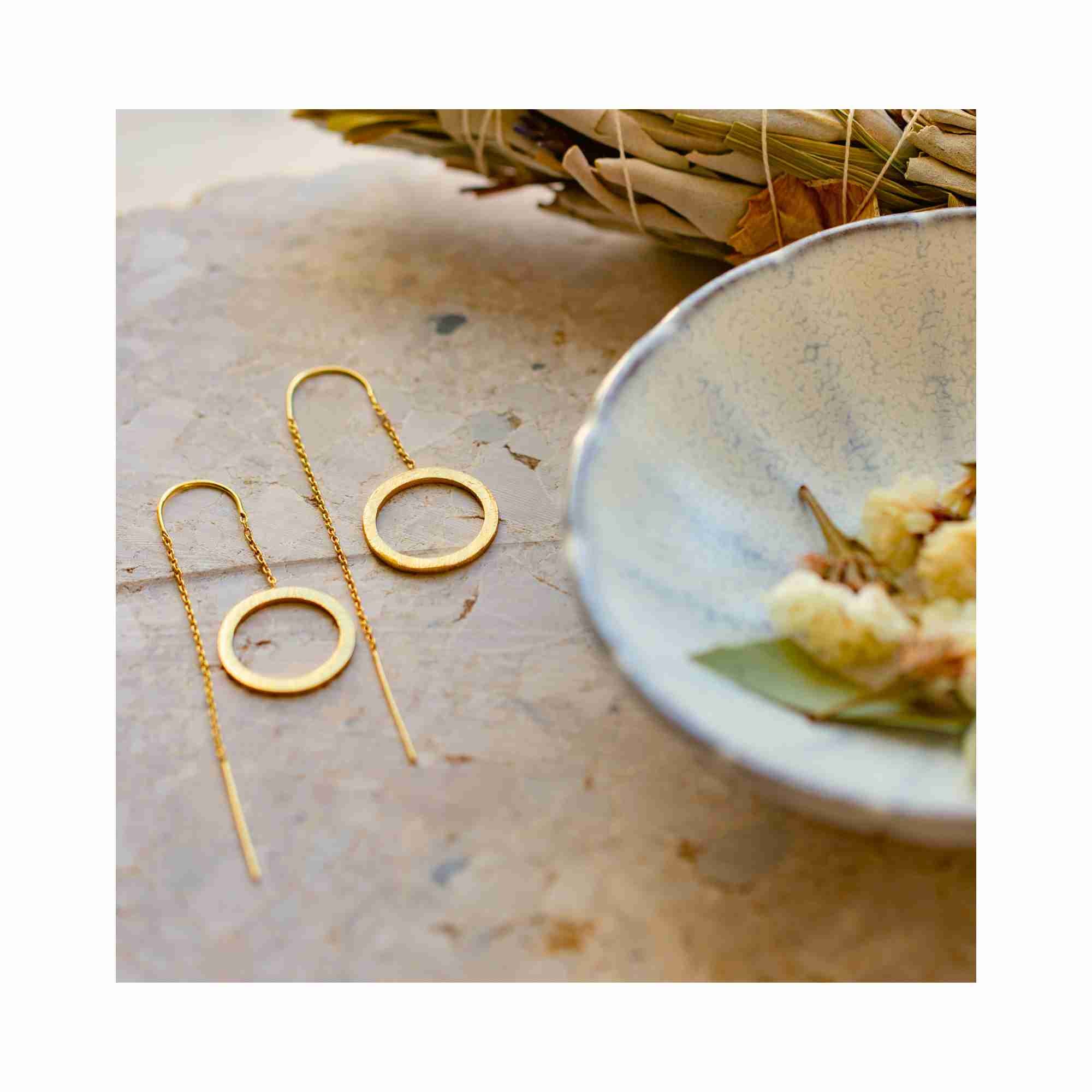 High-fashion editorial photoshoot featuring the Shimmering Disks gold circle chain threader earrings on a model with a natural buzz cut, emphasizing the bold yet lightweight architectural presence of Protsaah Zurich sustainable jewelry.