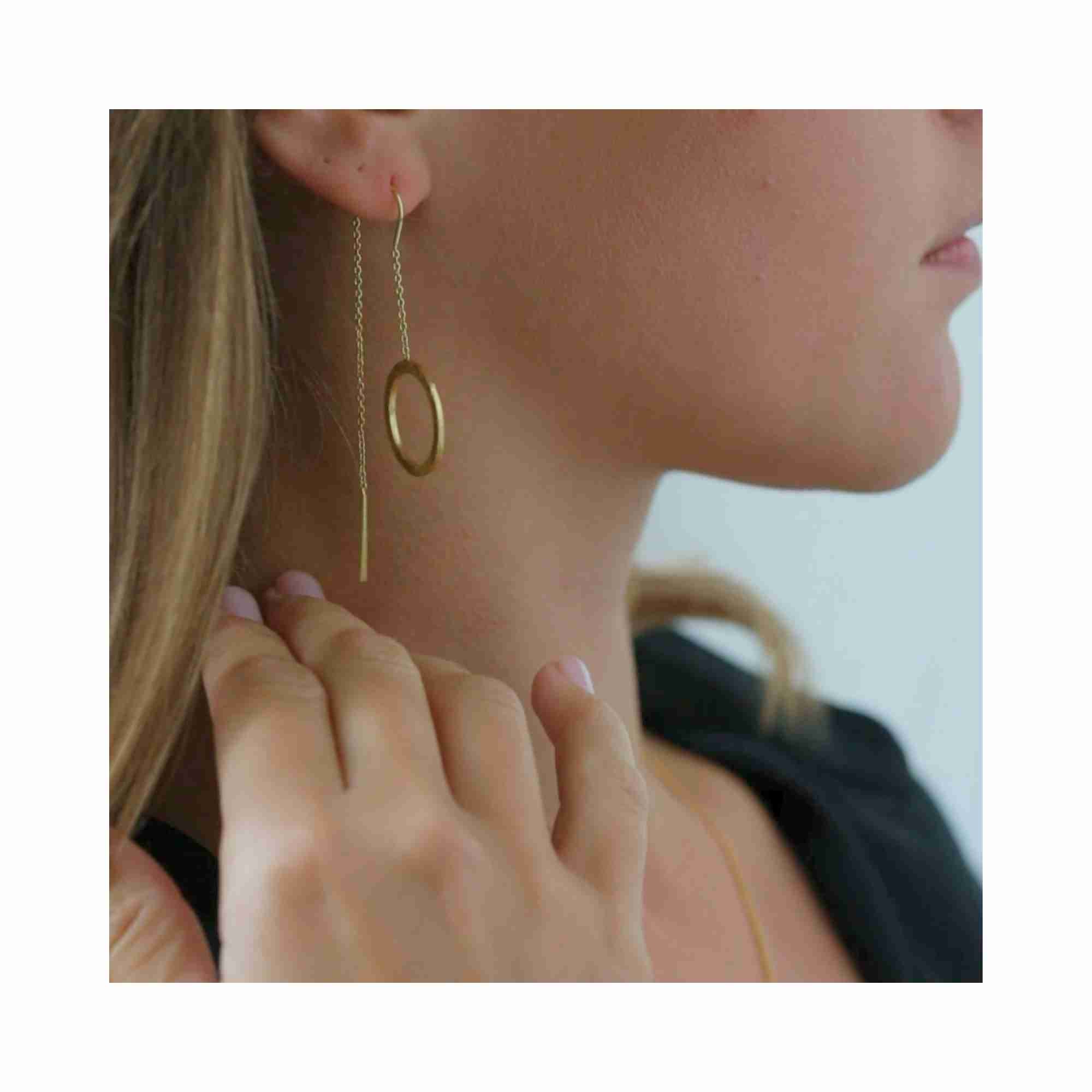 Still life photoshoot of Shimmering Disks circle chain threader earrings in 22K gold vermeil, artistically styled on a stone surface with a white ceramic bowl and dried sage to highlight the minimalist, organic design.
