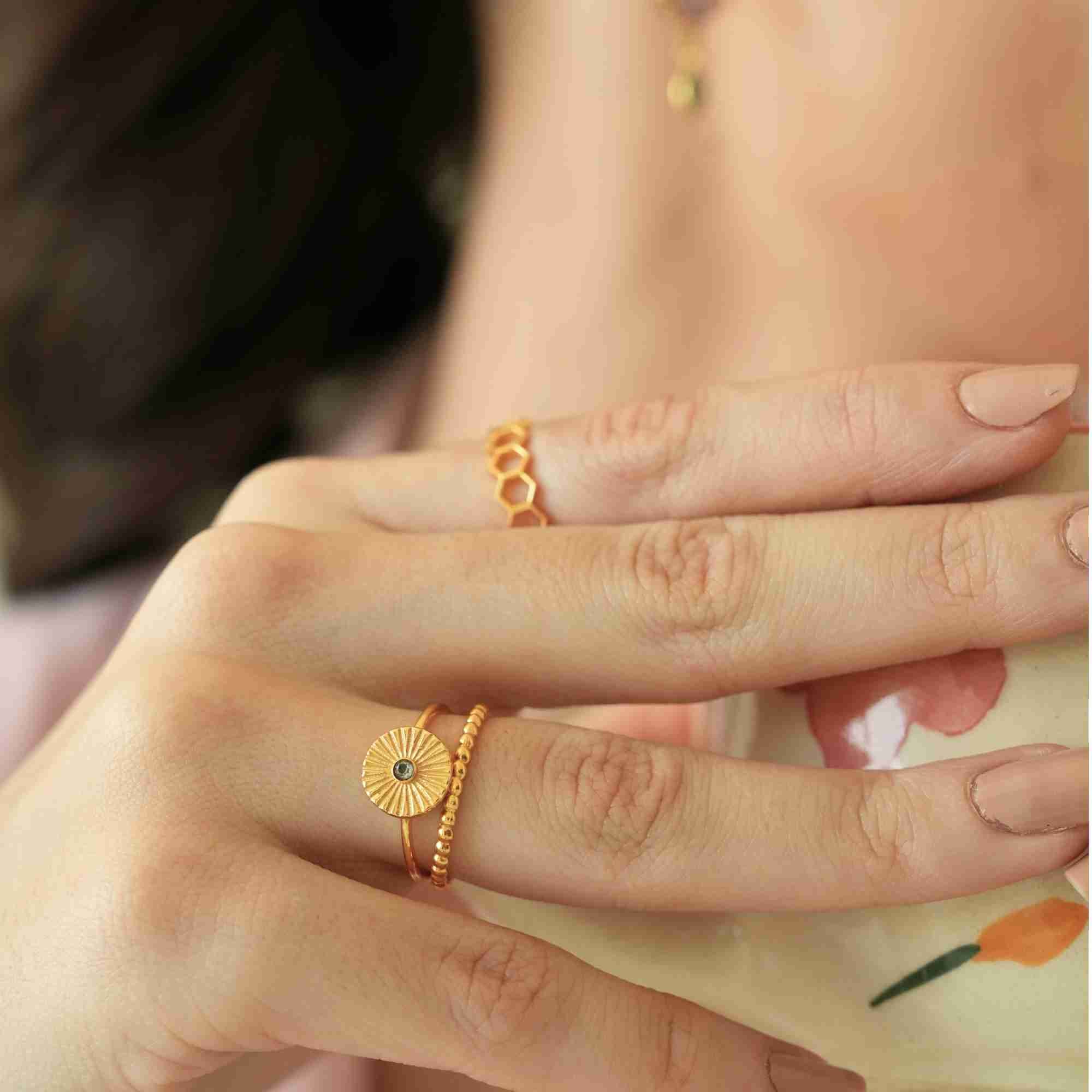 Profile shot of a model holding a floral ceramic teacup near her face, highlighting her coordinated ensemble featuring fine earrings, a necklace, and the Delicate Vintage Fluted Disc Ring in Gold by Protsaah Zurich.