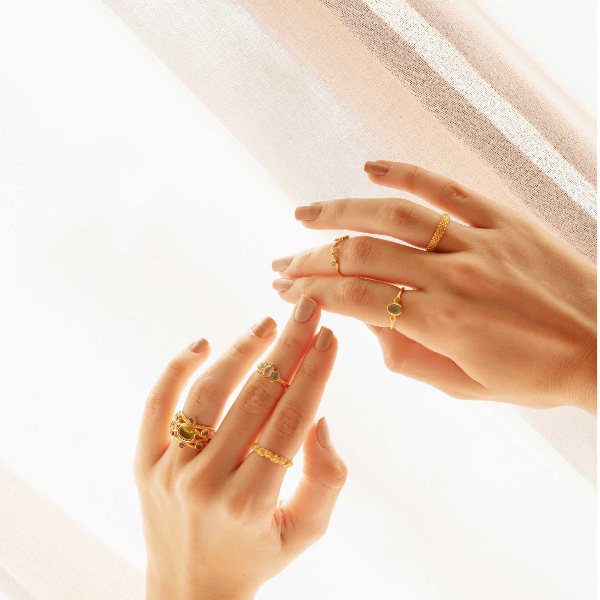 A gold adjustable ring featuring a small, bezel-set oval aqua chalcedony gemstone at its center, flanked by delicate metallic droplet accents on a smooth gold band.