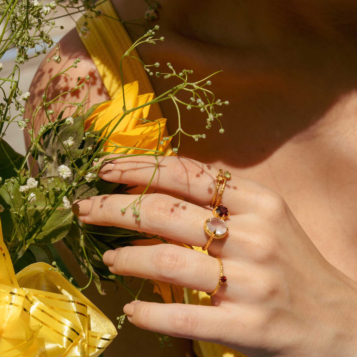 Delicate Vintage Aqua Chalcedony Dotted Band Ring Gold — Hand wearing a gold ring with an aqua chalcedony gemstone, holding yellow flowers. By Protsaah Zurich.