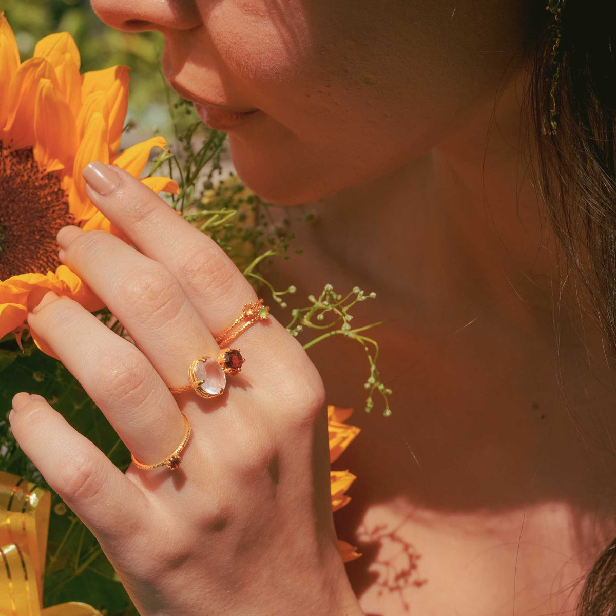 Delicate Vintage Aqua Chalcedony Dotted Band Ring Gold — Hand wearing a gold ring with an aqua chalcedony gemstone, holding yellow flowers. By Protsaah Zurich.