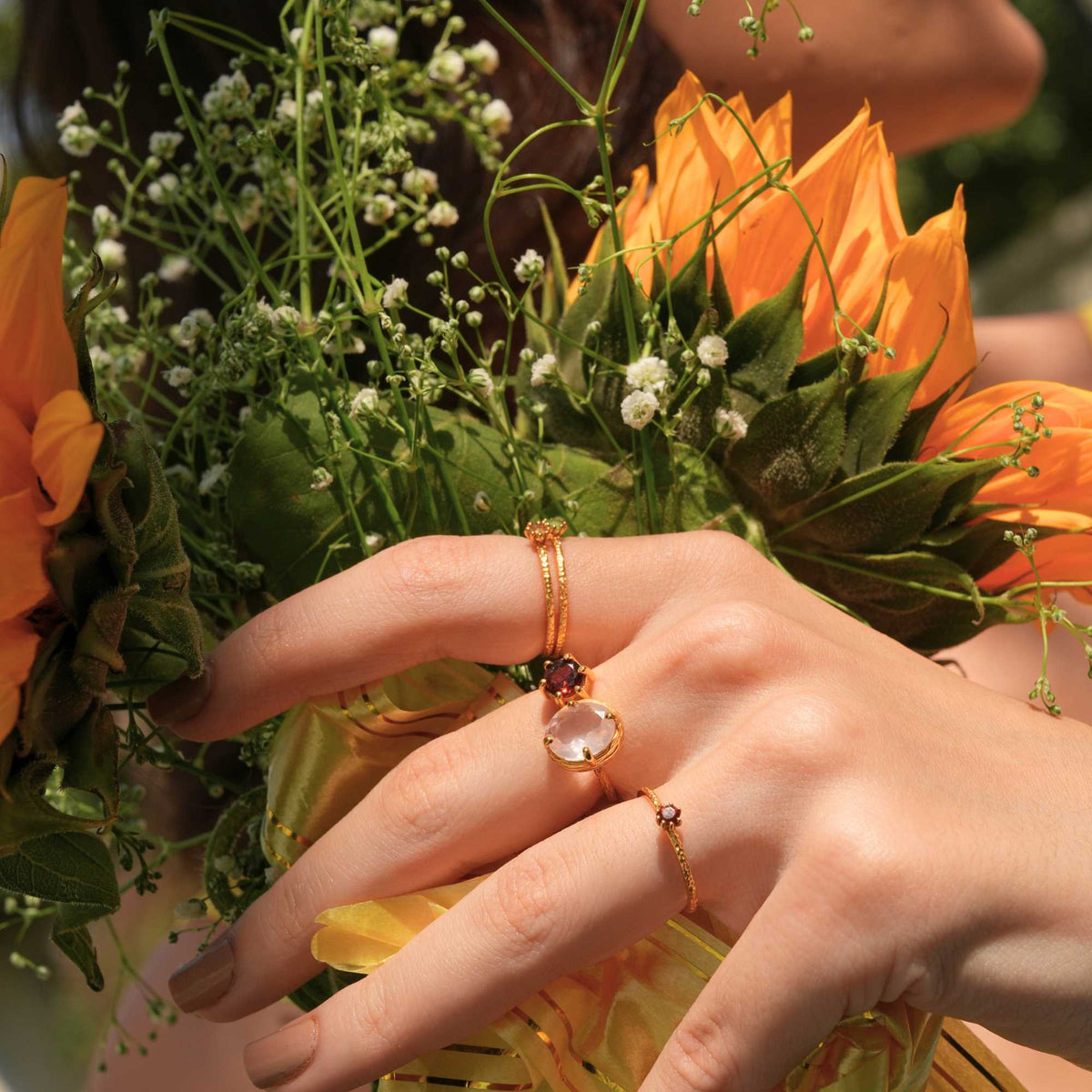 Delicate Vintage Aqua Chalcedony Dotted Band Ring Gold — Hand wearing a gold ring with an aqua chalcedony gemstone, holding yellow flowers. By Protsaah Zurich.