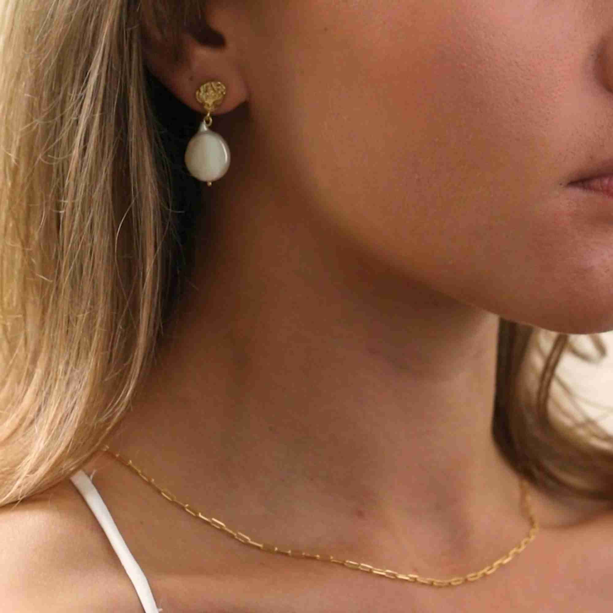 Side profile view of a blonde model wearing the gold PEARLS GALORE Molten Silver & Keshi Pearl Drop Earrings paired with a delicate gold paperclip chain necklace.
