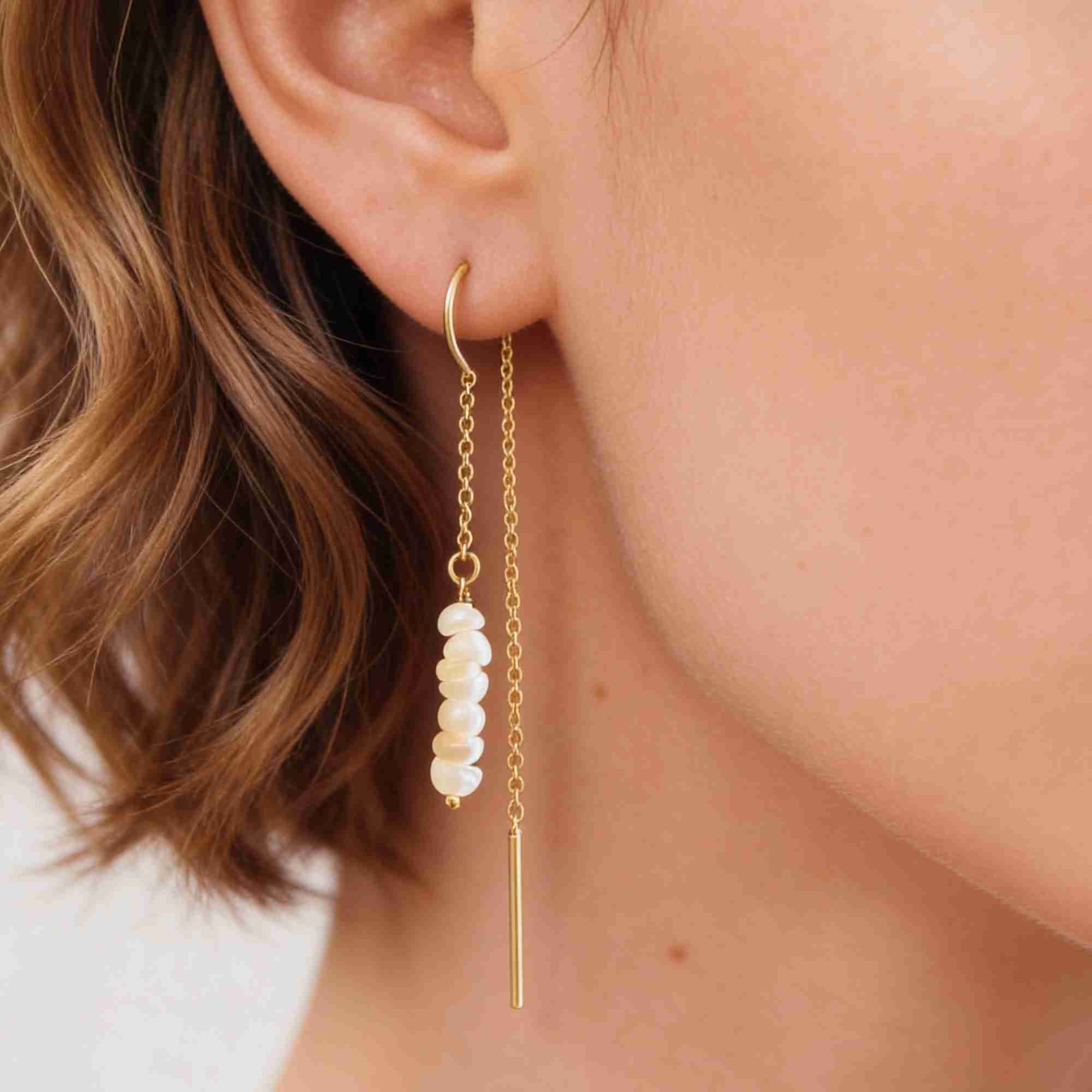 Extreme macro close-up shot highlighting the stacked row of small seed pearls, delicate gold chain, and gold bar drop on the model's ear.