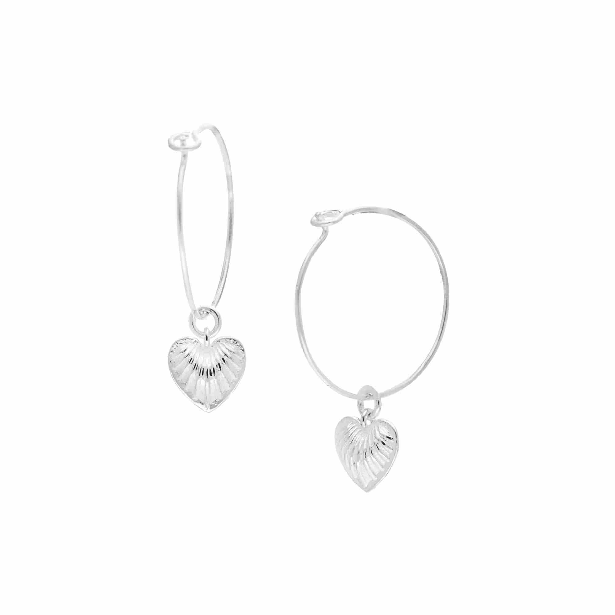 Queen of Charms Fluted Heart Charm Hoop Earrings Silver — delicate silver wire hoops with a textured radiating heart charm drop by Protsaah Zurich.