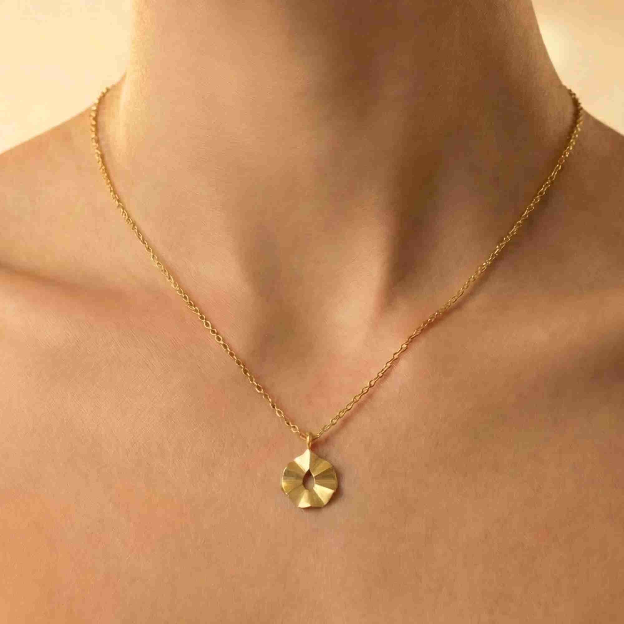 Close-up lifestyle view named Ribbon & Lace showing a model wearing the Ribbons & Lace Ruffle Furls Pendant Necklace Gold, highlighting the delicate gold link chain adorned with a small, round pendant featuring three-dimensional ruffled folds and a hand-brushed matte finish by Protsaah Zurich.