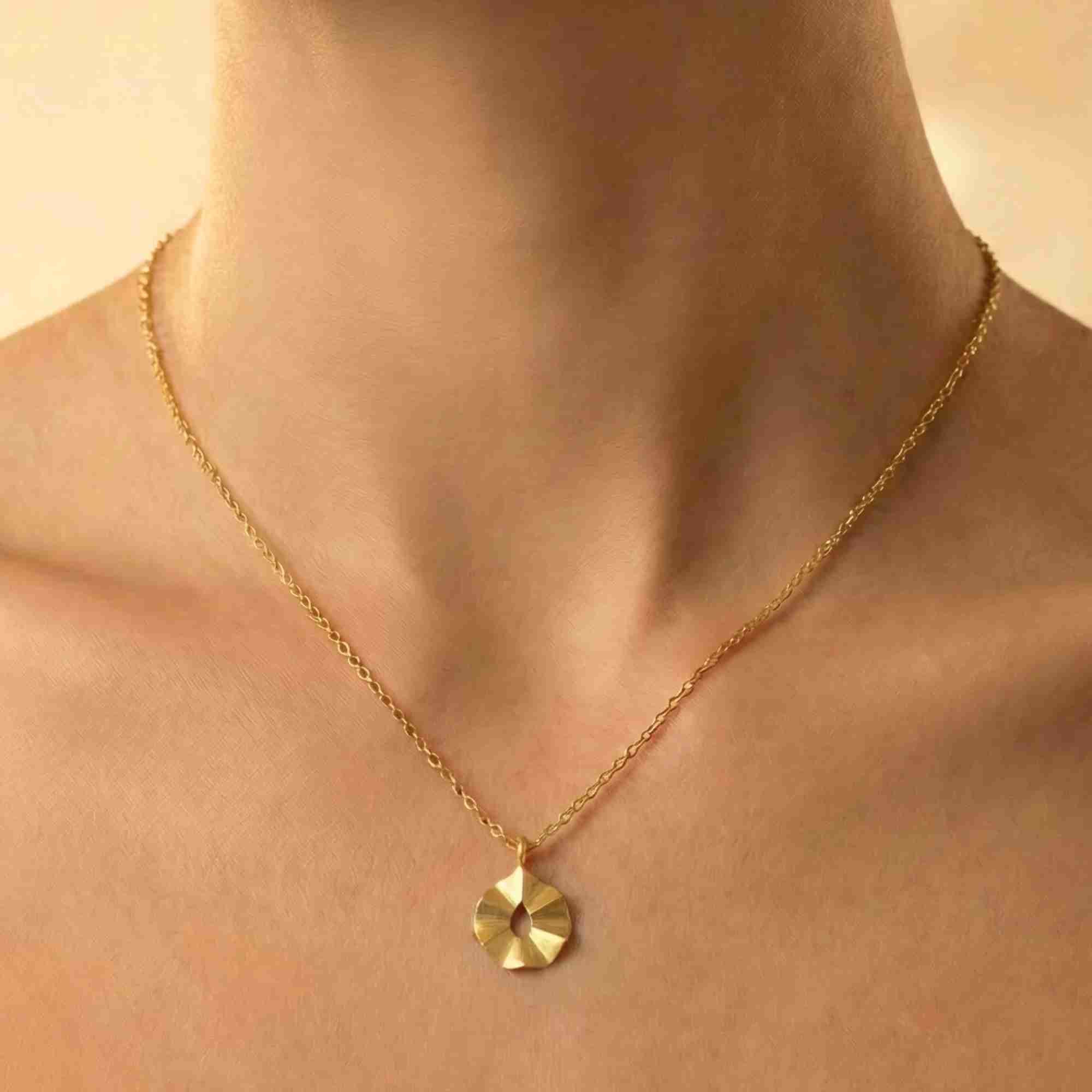 Close-up lifestyle view named Ribbon & Lace showing a model wearing the Ribbons & Lace Ruffle Furls Pendant Necklace Gold, highlighting the delicate gold link chain adorned with a small, round pendant featuring three-dimensional ruffled folds and a hand-brushed matte finish by Protsaah Zurich.