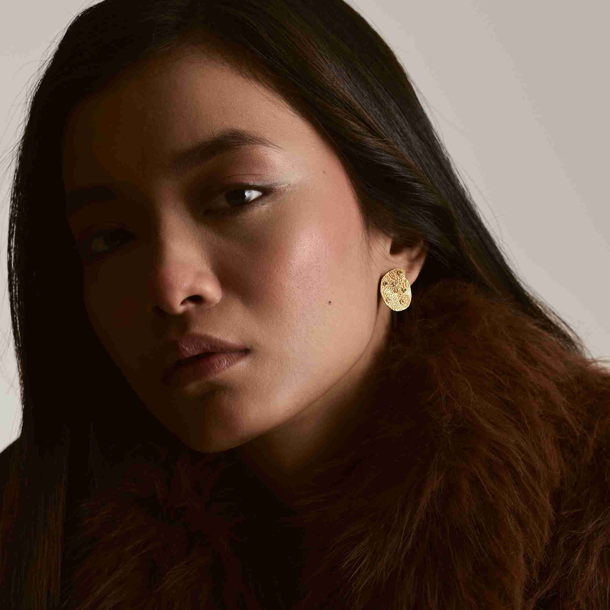 Direct studio portrait of a model wearing the gold Ribbons and Lace Galaxy Multi-Gemstone Stud Earrings styled with a rich brown fur collar.