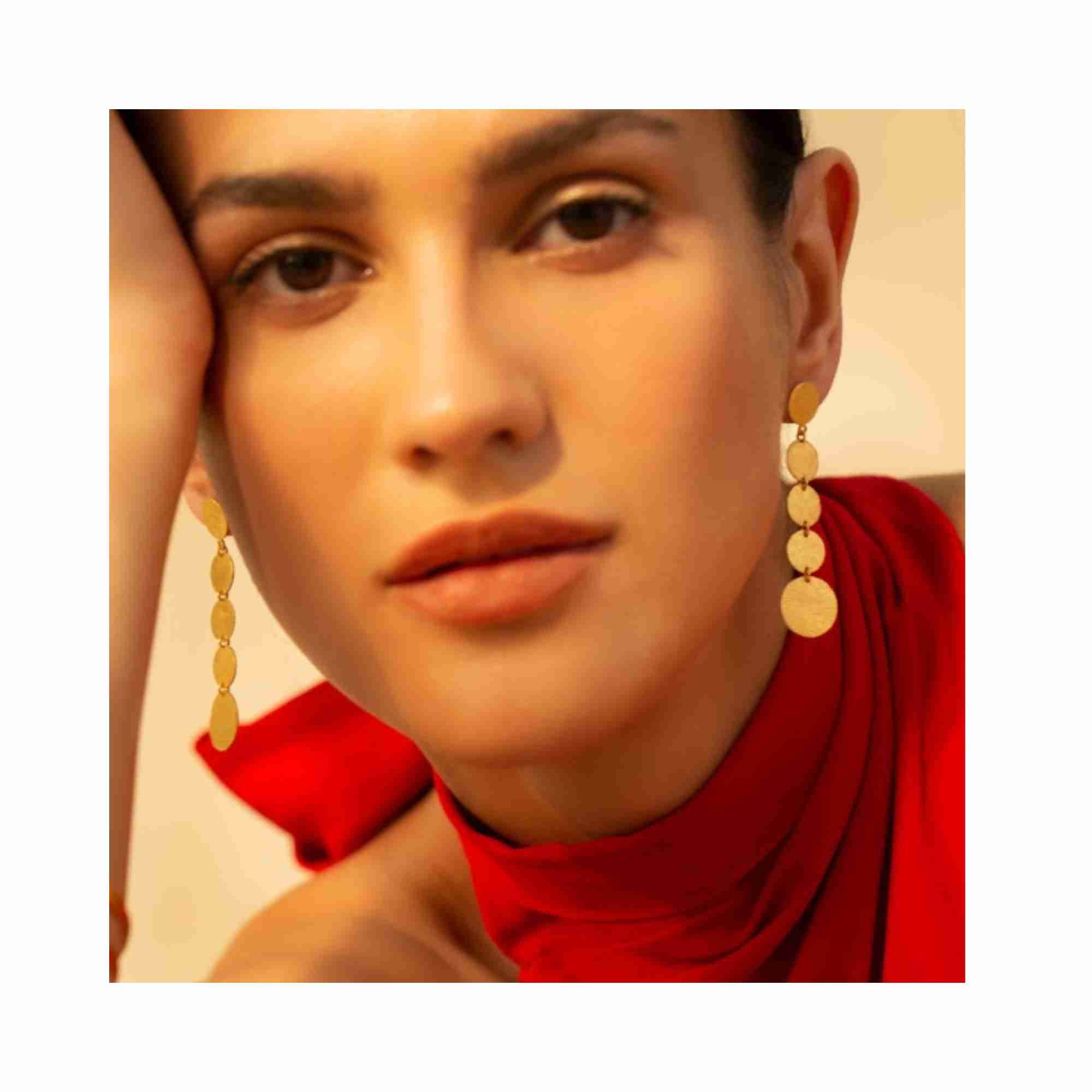 Close-up product photoshoot of Shimmering Disks Graduating Disc Cascade earrings, showcasing the intricate hand-applied scratch finish and signature matte texture on 22K gold vermeil — Protsaah Zurich.
