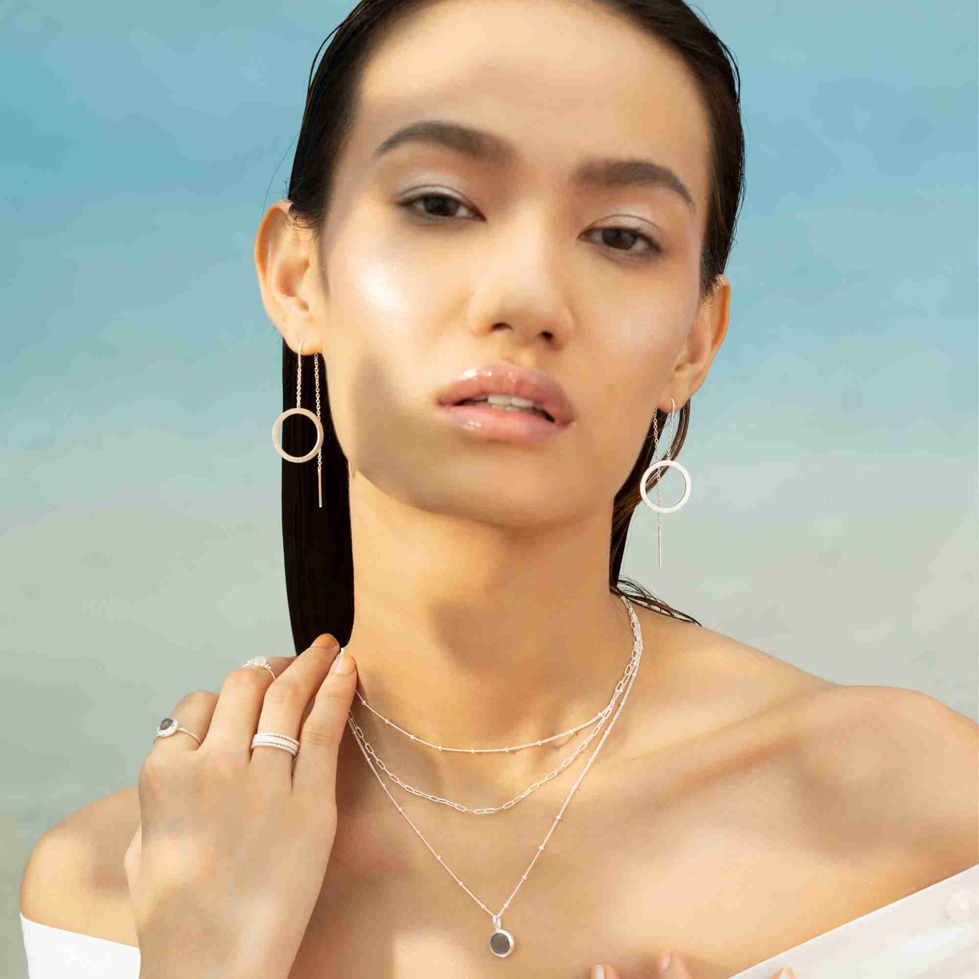 Close-up product perspective of Shimmering Disks Circle Chain Threader Earrings Silver, showing the fluid connection point between the minimalist box chain and the handcrafted geometric silver disk dangle.