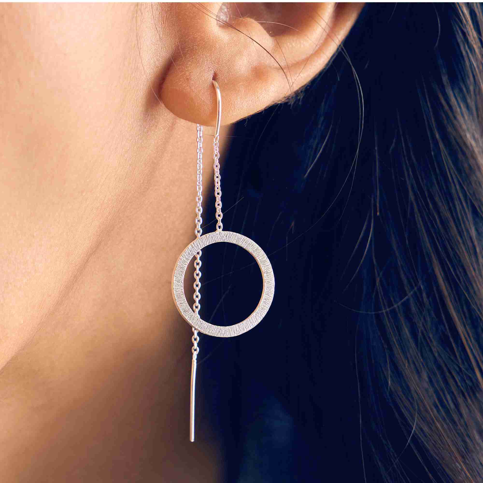 Close-up detail of the sterling silver Shimmering Disks Circle Chain Threader Earring, highlighting the hand-brushed circular pendant and fine bar threader.