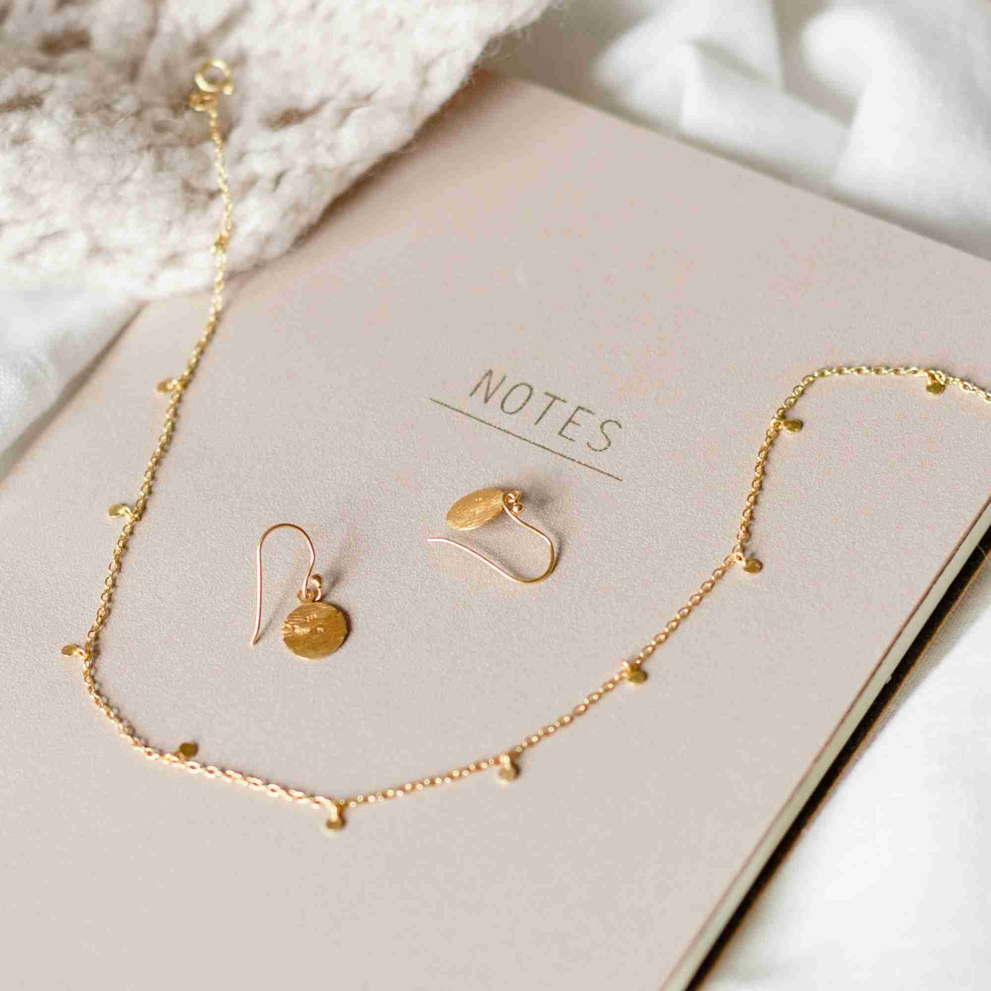 Close-up view of a model wearing the gold Shimmering Disks Constellation Disc Chain Necklace resting delicately along her collarbone.