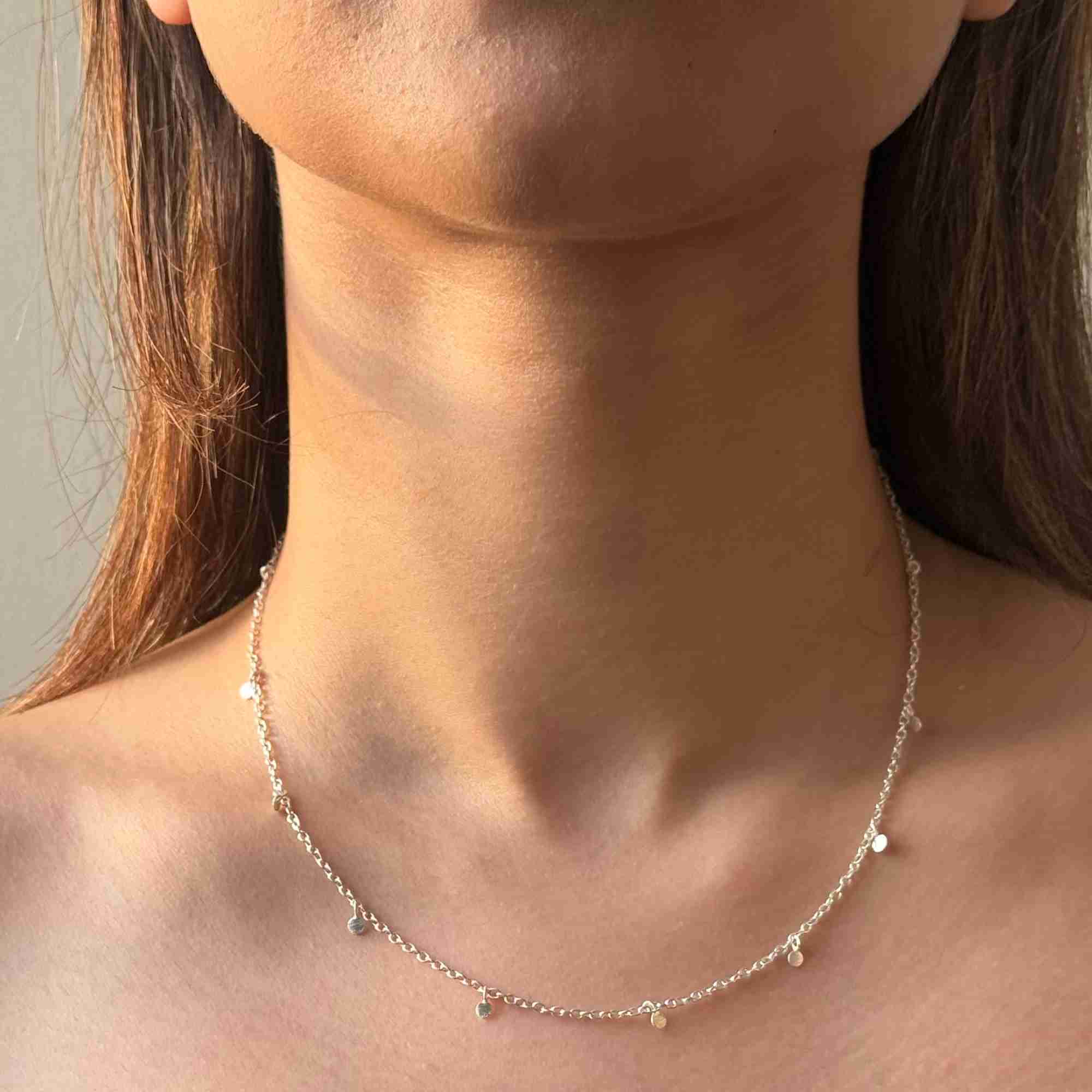 Front-facing view of a model wearing the delicate silver Shimmering Disks Constellation Disc Chain Necklace along the base of her neck.