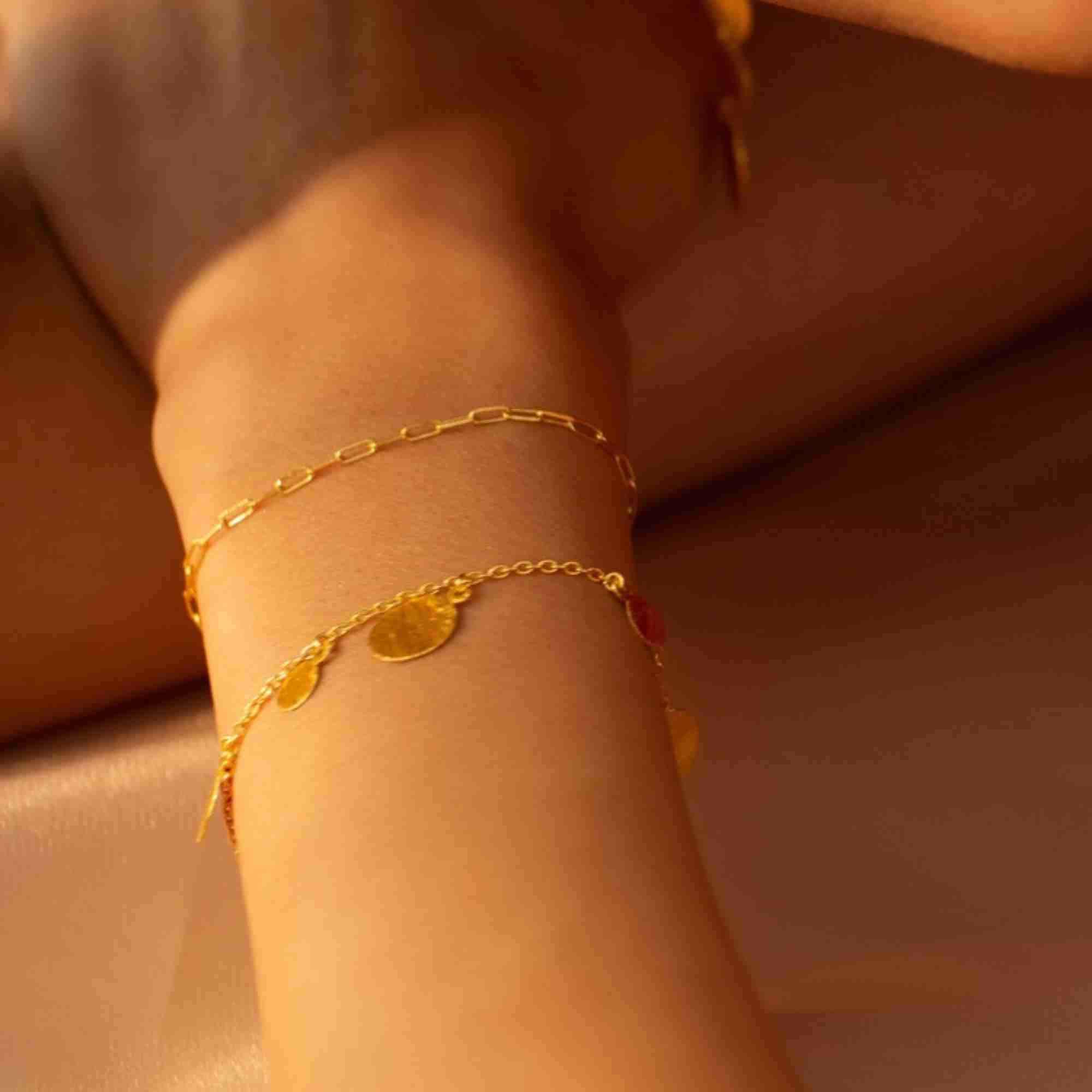 Detailed close-up photo of the Shimmering Disks Delicate Chain Bracelet Gold centerpiece, showcasing the small circular gold disc charm with its fine hand-brushed matte finish.