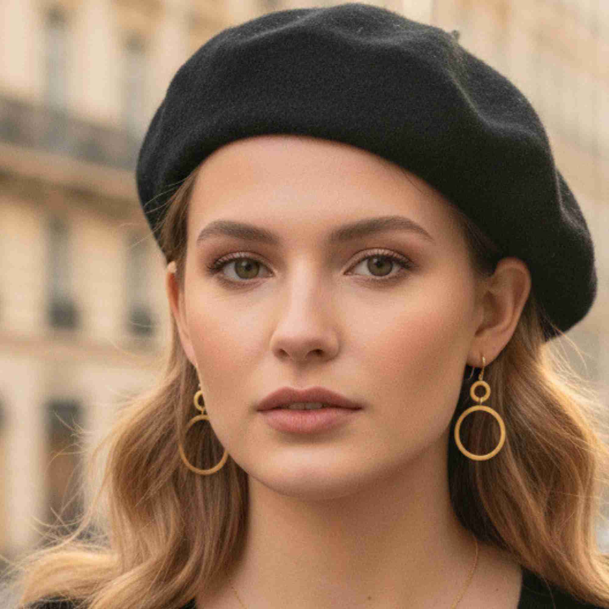 Studio product shot of Shimmering Disks Dual Circle Statement Earrings Gold laid flat on a white textured plate, showing the two interconnected, overlapping circular discs with a brushed matte finish.