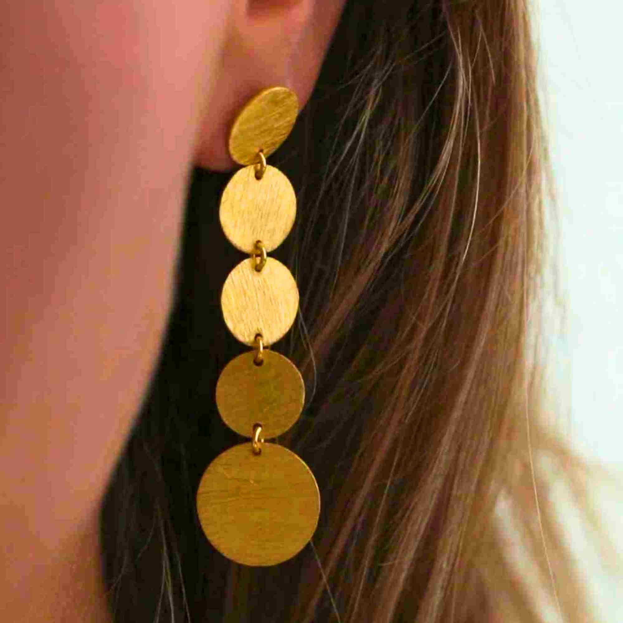 Model wearing Shimmering Disks Graduating Disc Cascade Statement Earrings Gold, showcasing how the vertical triple-disc tier cascades down smoothly from the earlobe.
