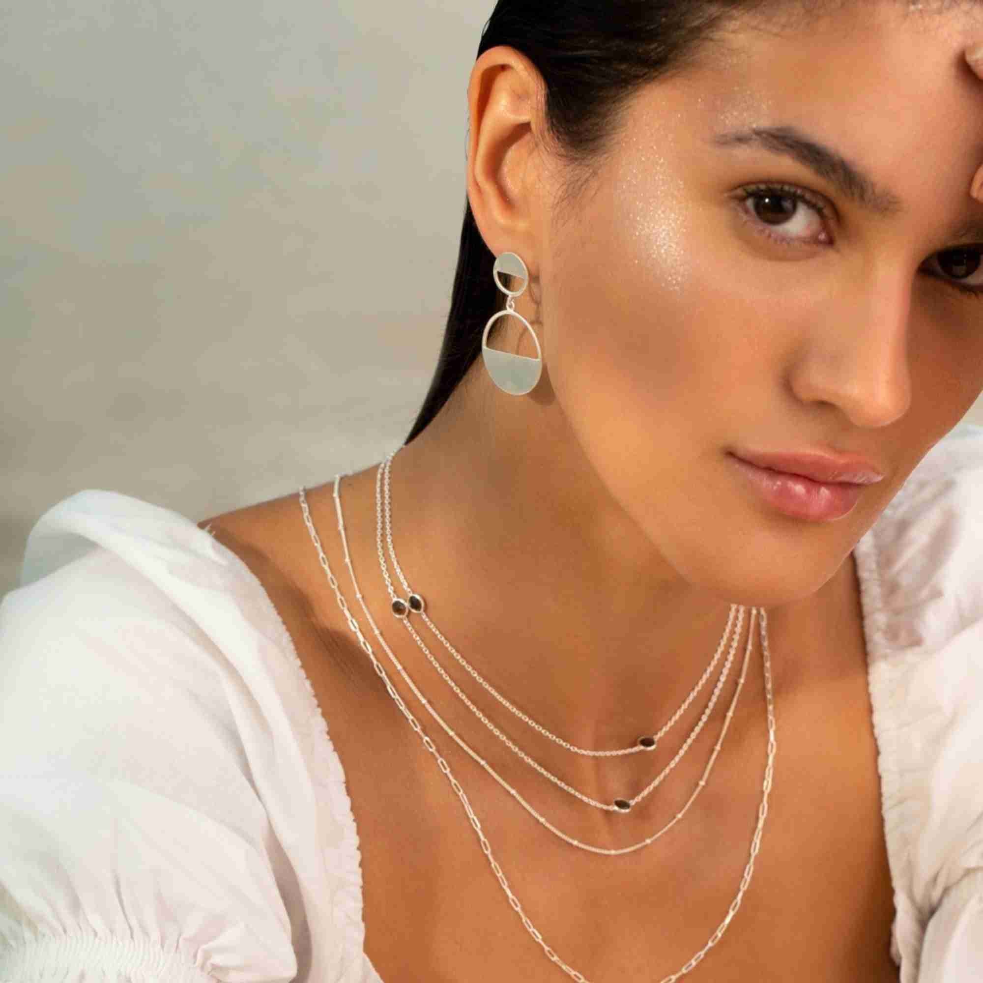 Detailed close-up view of Shimmering Disks Horizon Duo Drop Statement Earrings Silver, showcasing the delicate link connection between the geometric elements and the fine handcrafted scratch finish.