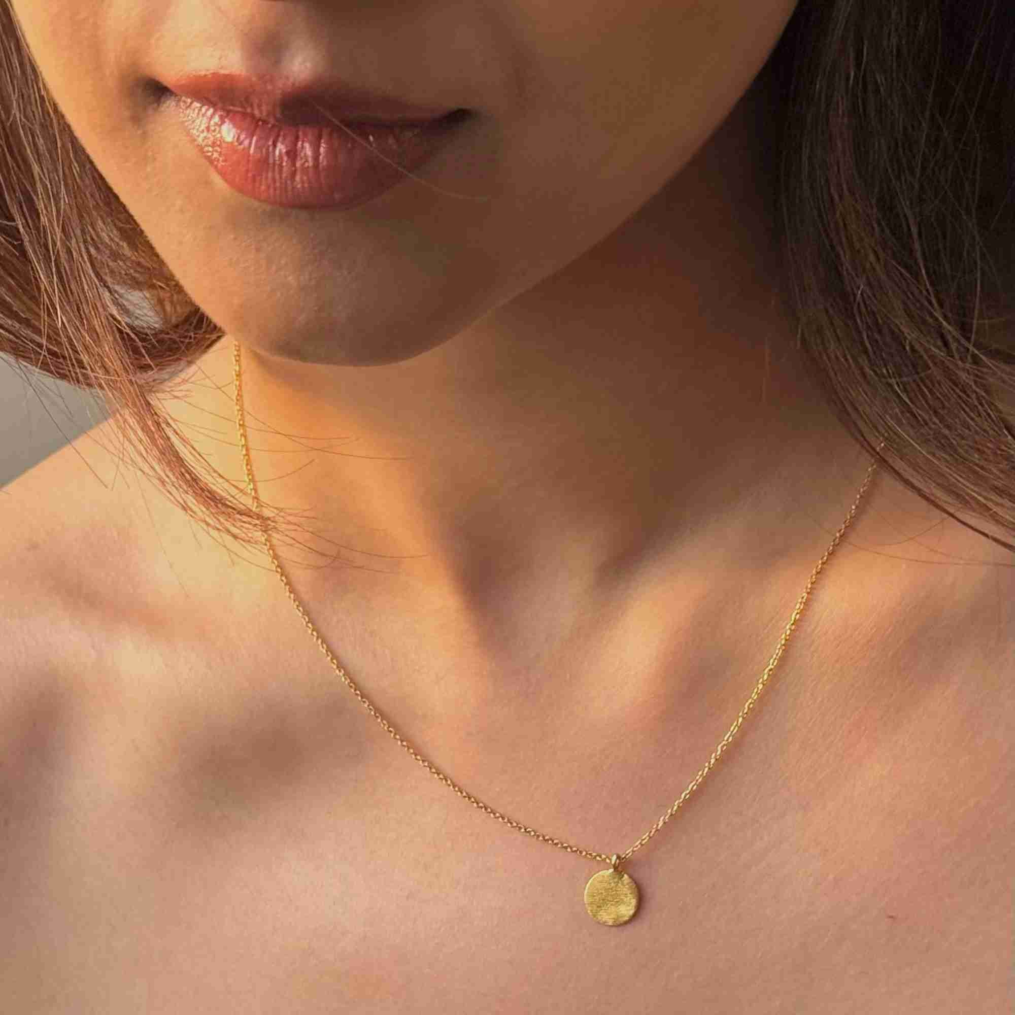Model wearing the gold Shimmering Disks Minimalist Coin Pendant Necklace, featuring a delicate fine chain and small brushed-finish circular disk.