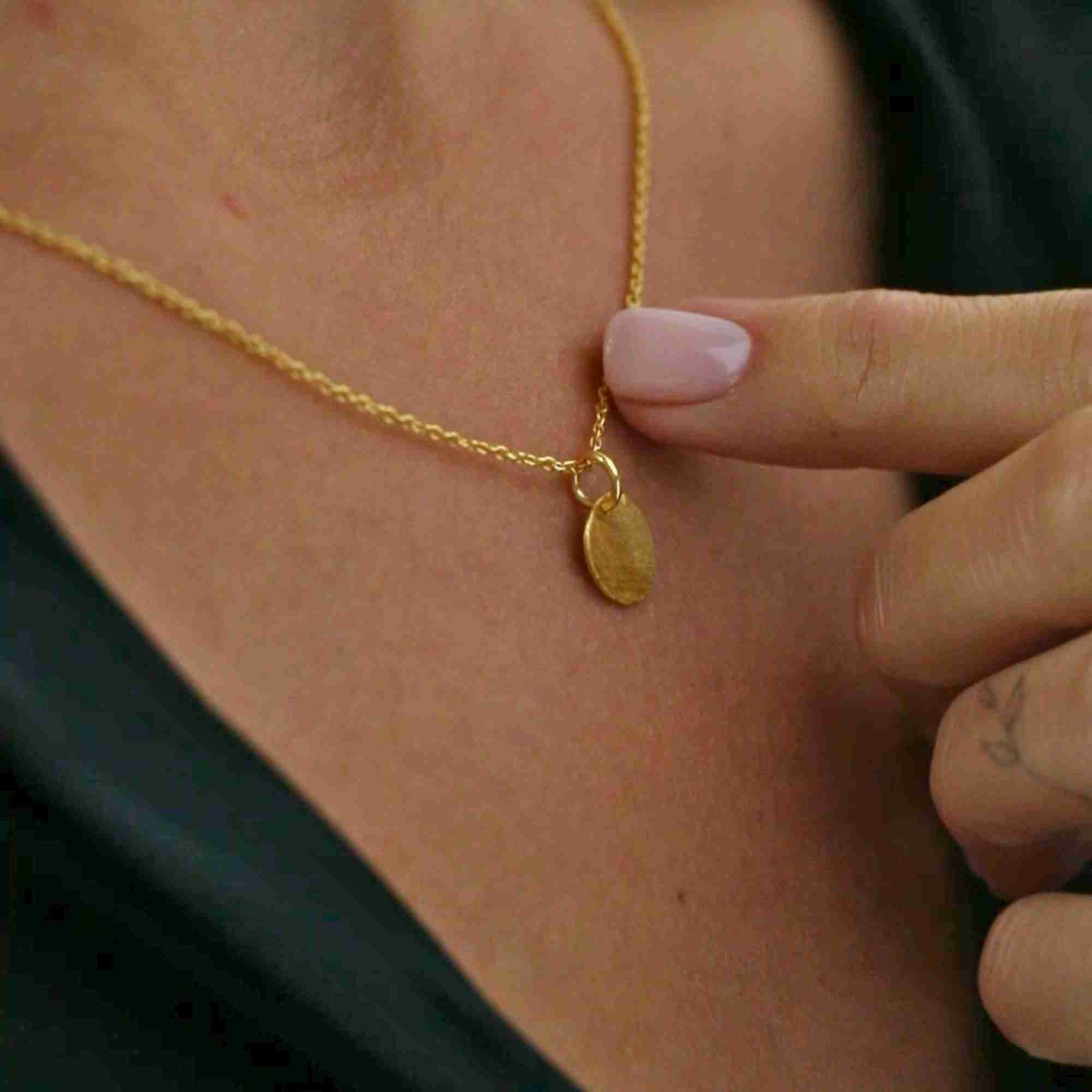 Macro close-up shot showing the side angle, bail loop connection, and delicate link chain of the gold Shimmering Disks Minimalist Coin Pendant Necklace.