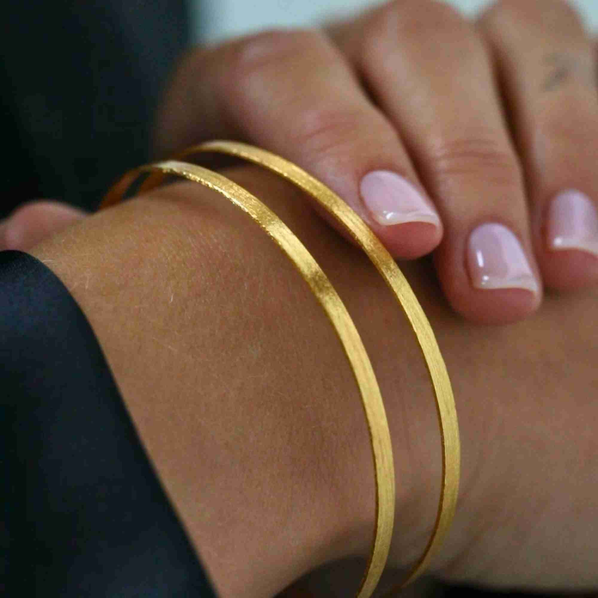 Close-up detail view highlighting the hand-brushed gold texture and sleek geometry of the Shimmering Disks Sculptural Flat-Band Double Cuff.