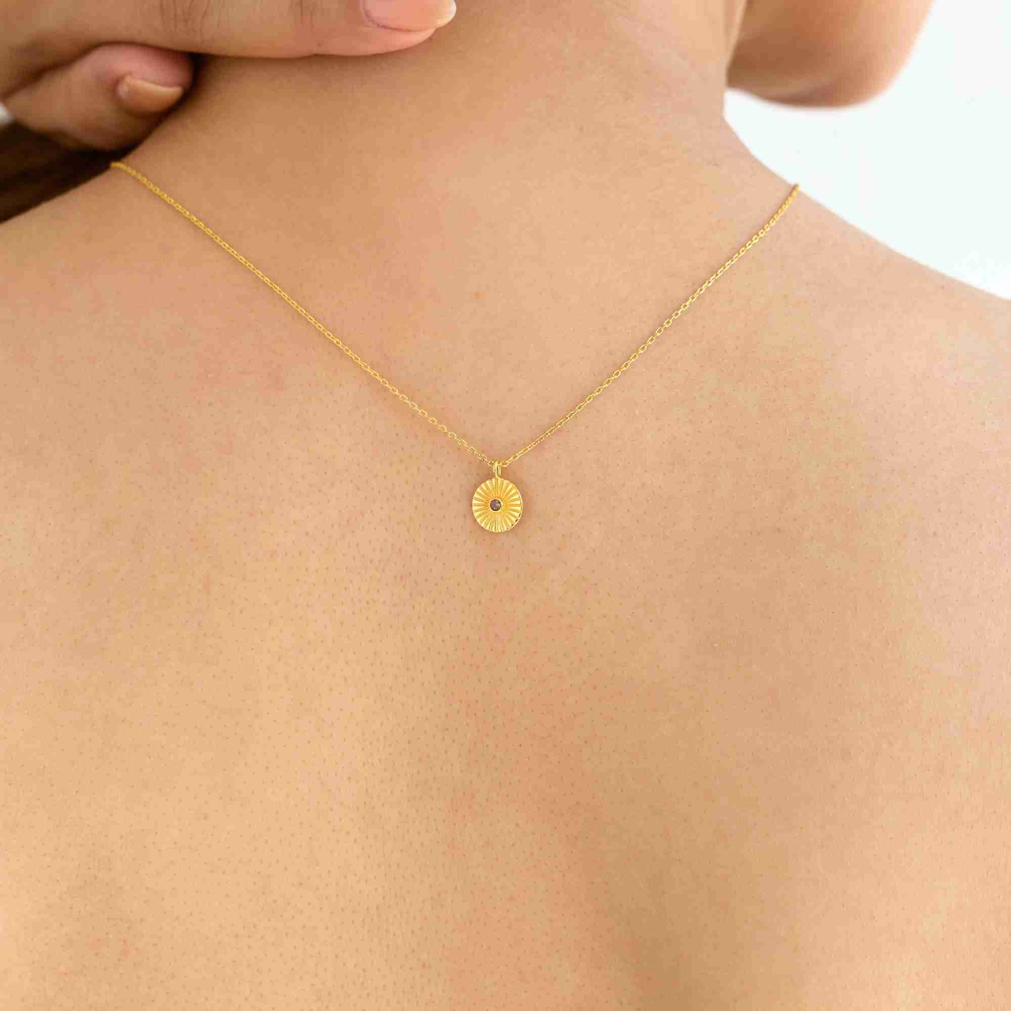 Rear lifestyle view of a model wearing the Delicate Vintage Labradorite Fluted Medallion Coin Pendant Necklace Gold, referencing file name Delicate_Vintage.jpg. The shot highlights the fine gold chain and the small, sunburst-grooved gold coin pendant resting gracefully against her upper back.